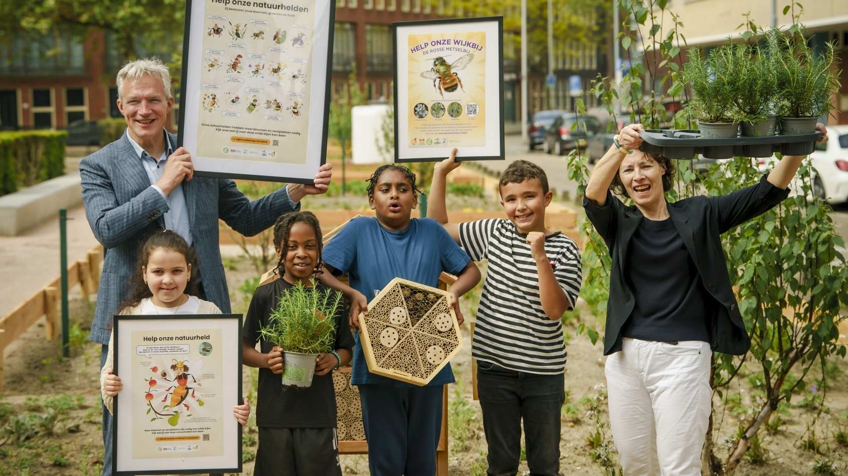 Gedeputeerde Berend Potjer en Ingeborg Berger, programmamanager Biodiversiteit Rotterdam, planten met de kinderen van kindcentrum De Vlinder rozemarijnplantjes voor de wijkbijen.